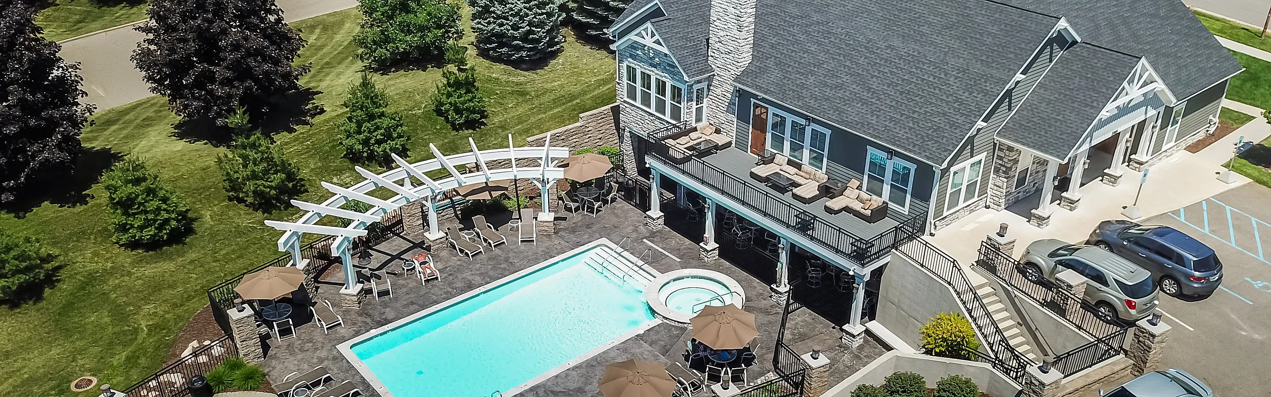 Aerial view of a luxurious residential building with a sparkling pool, elegant outdoor seating, and lush greenery.