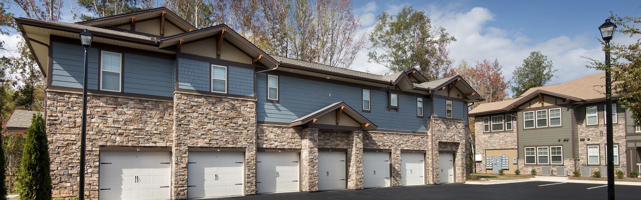 Charming two-story residential building with a stone facade and attached garages, nestled in a serene suburban neighborhood.
