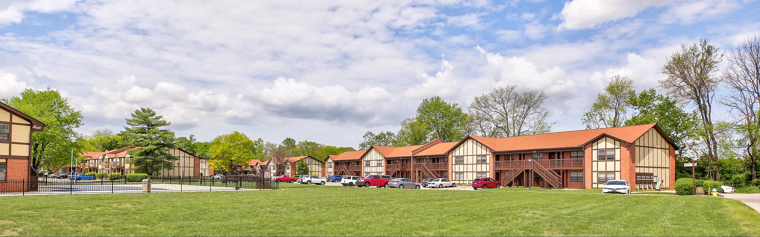 Charming apartment complex with Tudor-style architecture and lush green surroundings, offering a serene residential atmosphere.