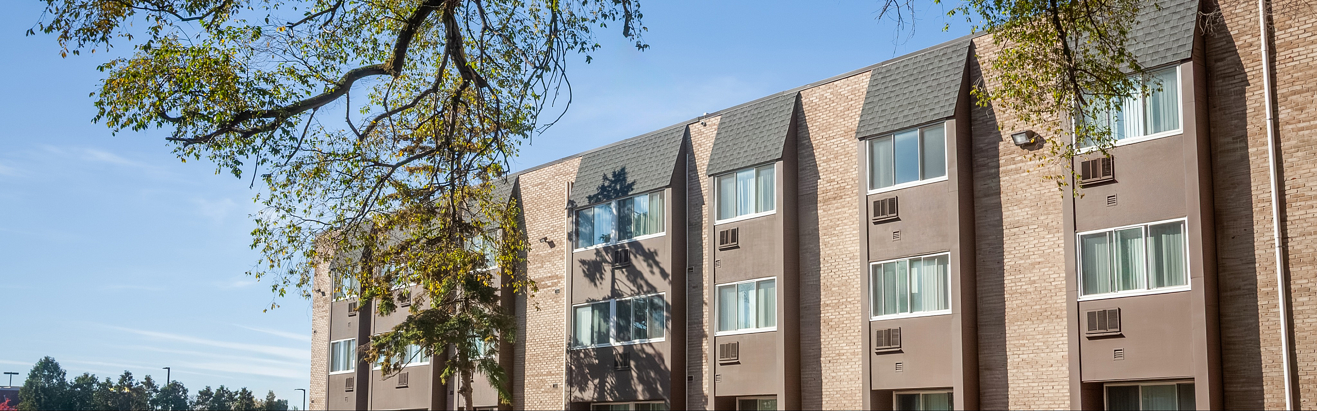 Charming apartment building with large windows, nestled among lush greenery, capturing modern suburban living.