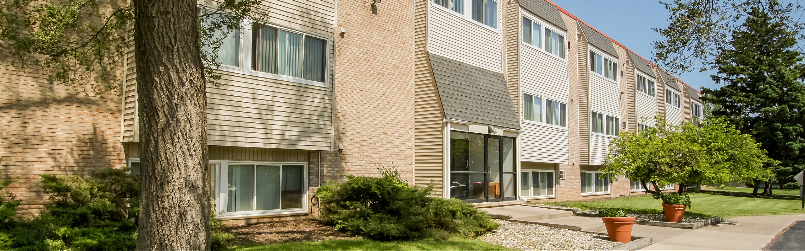 Charming apartment complex with modern architecture, large windows, and lush greenery.