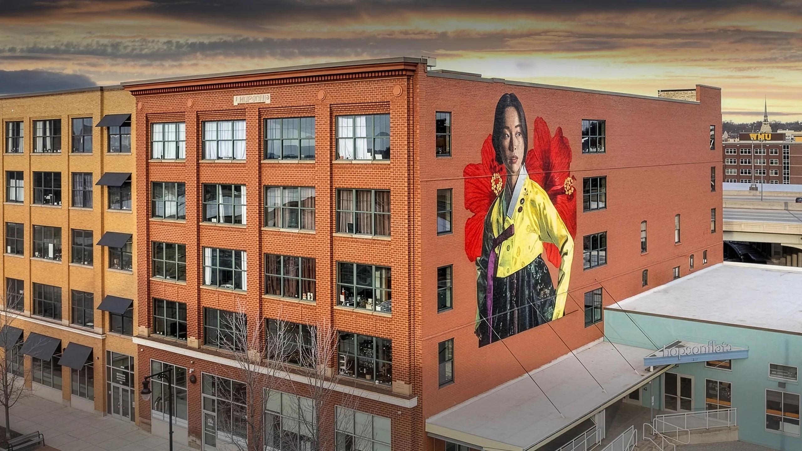 Modern urban building showcasing vibrant mural art, set against a serene sunset backdrop, capturing creative city living.