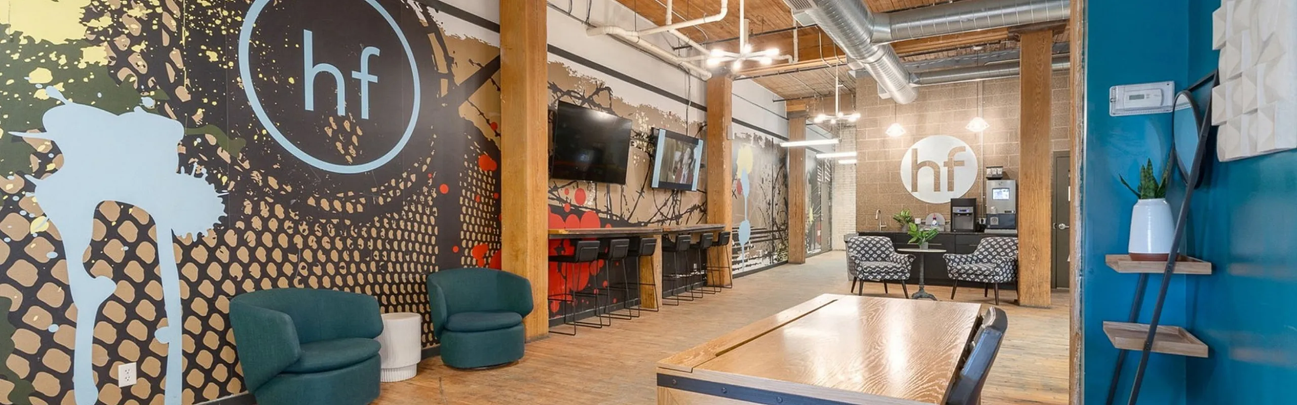 Chic industrial-style apartment lobby featuring bold graphic artwork, cozy seating, and modern lighting.