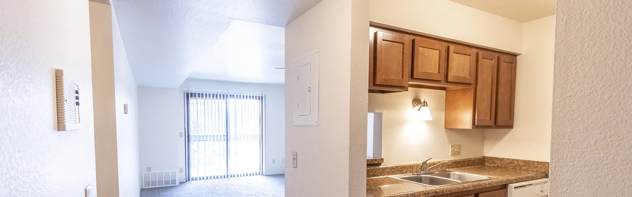 Bright and modern apartment interior featuring an open-plan living area with sliding glass doors and an elegant kitchen with granite countertops.