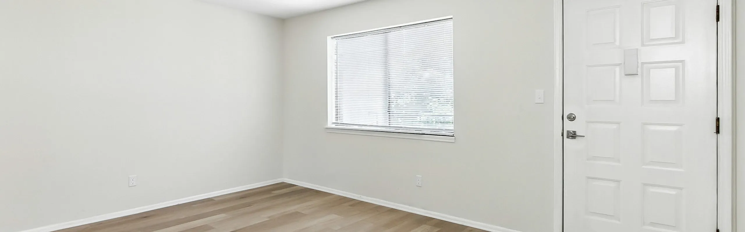 Bright and airy room with fresh white walls and large window, offering a modern and inviting atmosphere.