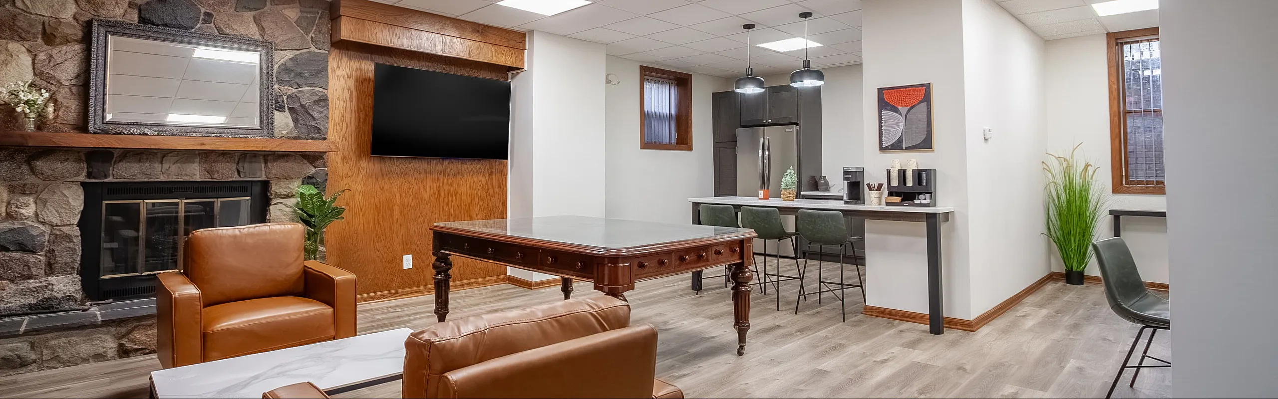 Contemporary living room with elegant stone fireplace, comfortable leather seating, and a sleek modern kitchen area.