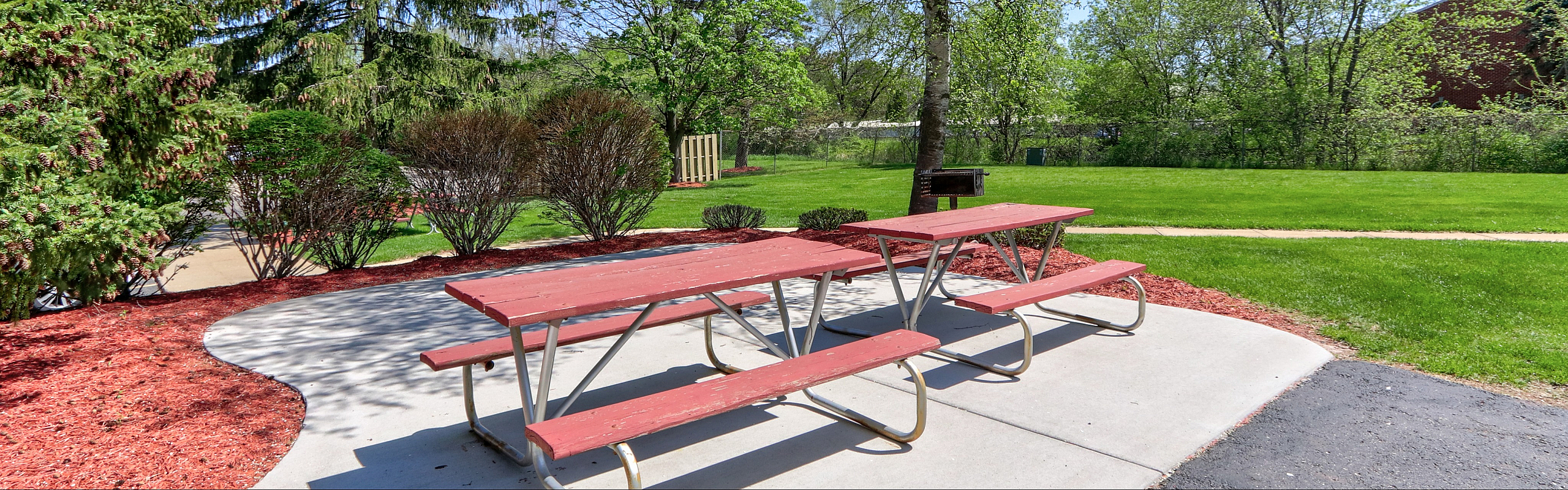 Charming outdoor picnic area with wooden tables set amidst lush greenery, perfect for enjoying nature.