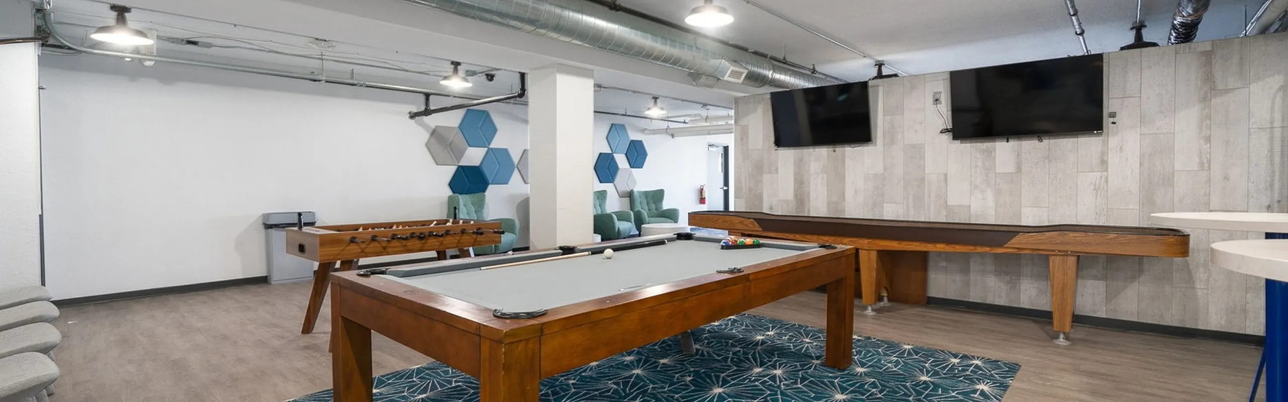 Modern recreation room featuring a stylish pool table, foosball, and vibrant geometric wall decor.