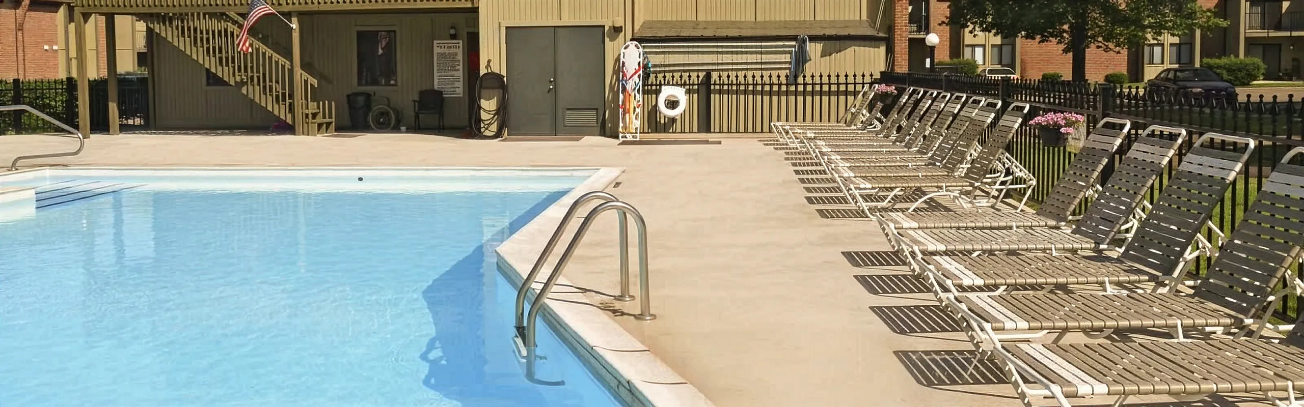 Inviting outdoor pool area with sun loungers perfect for relaxing, surrounded by a well-maintained patio in a tranquil setting.