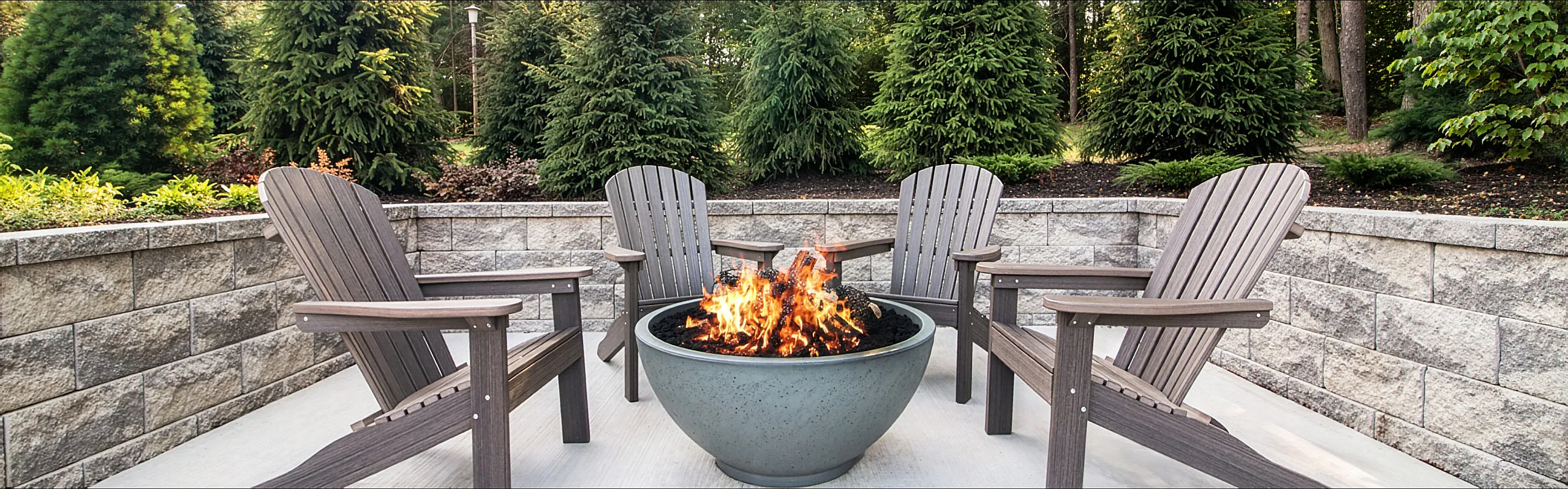 Charming outdoor patio featuring cozy wooden chairs around a modern fire pit, surrounded by lush greenery for a tranquil retreat.