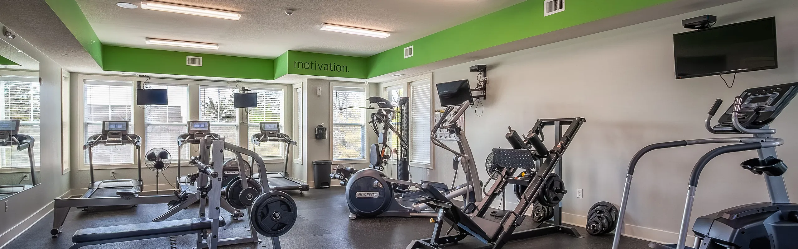 Bright and modern fitness center with state-of-the-art equipment, motivational signage, and ample natural light.