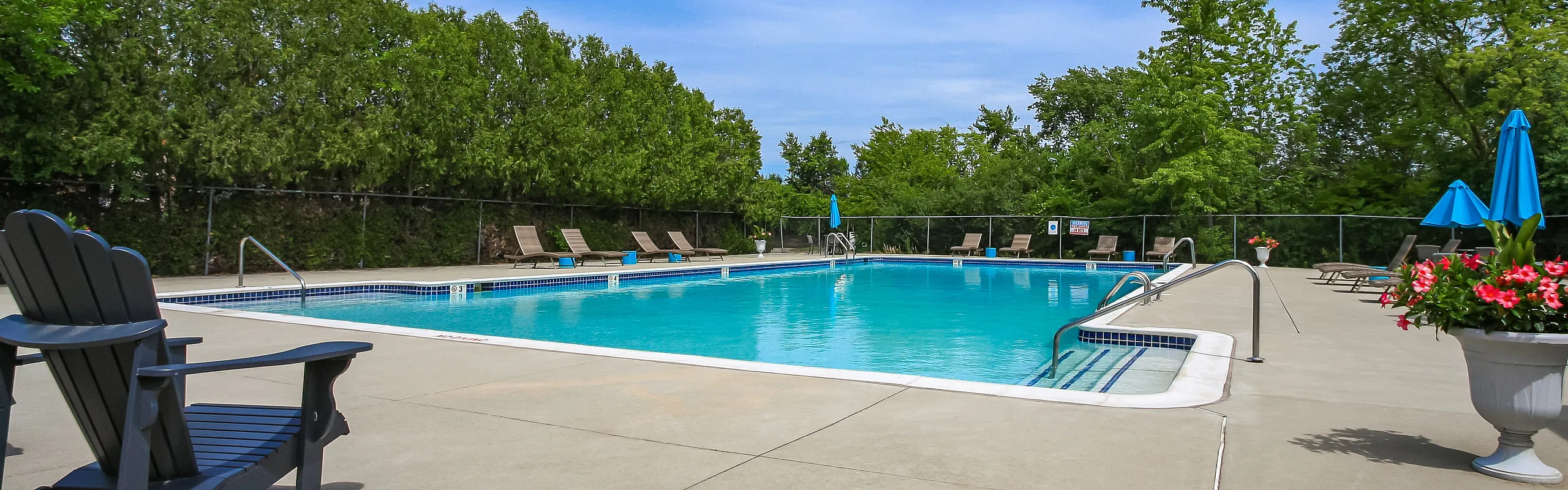 Inviting outdoor swimming pool surrounded by lush greenery and sun loungers, perfect for a relaxing retreat.