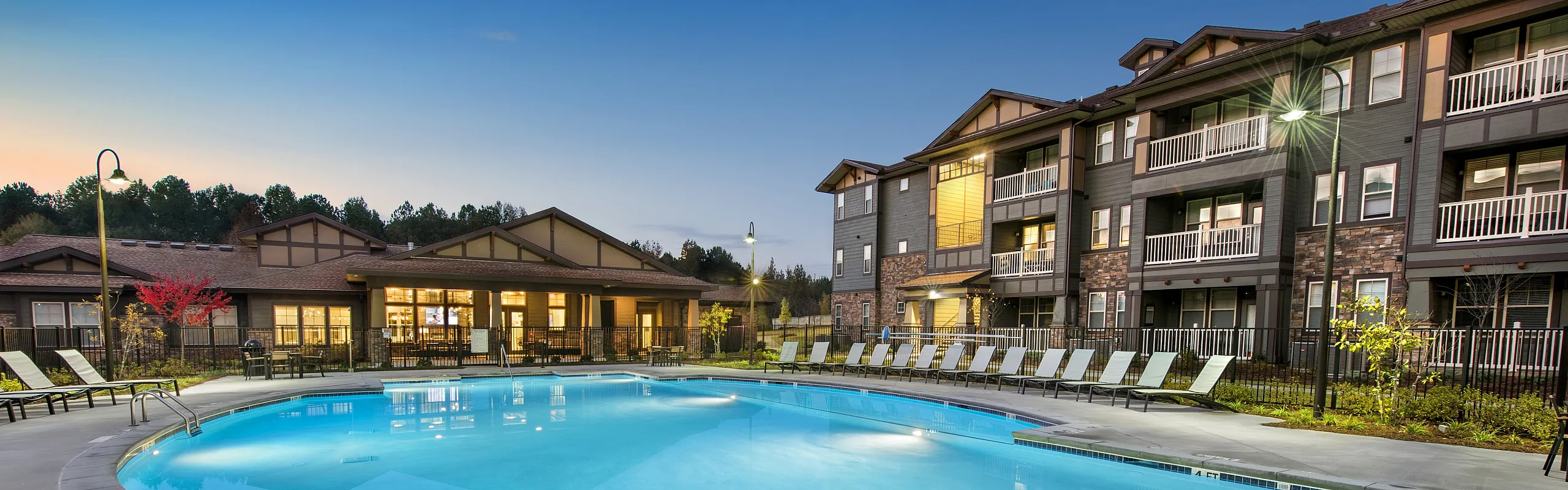 Charming apartment complex with a serene pool and elegant lounge area at sunset, offering a perfect blend of comfort and style.