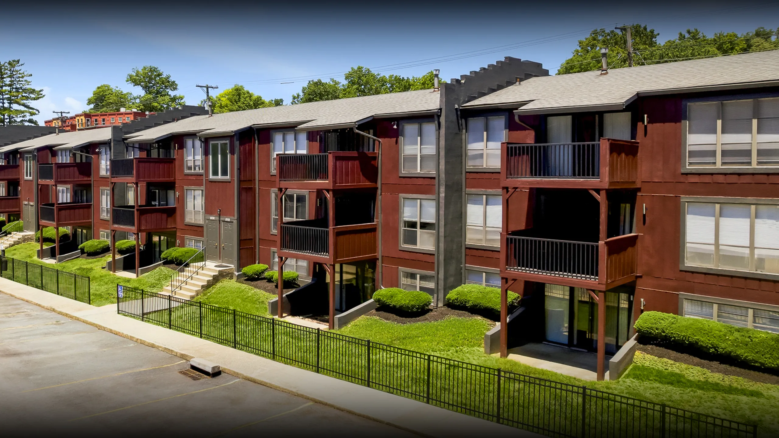 Charming apartment complex with redwood exterior, featuring spacious balconies and lush green surroundings, perfect for modern living.