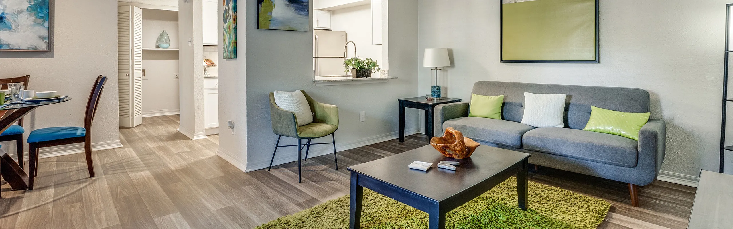 Contemporary open-plan living area with stylish gray sofa, vibrant green accents, and elegant wooden dining set, perfect for modern living.