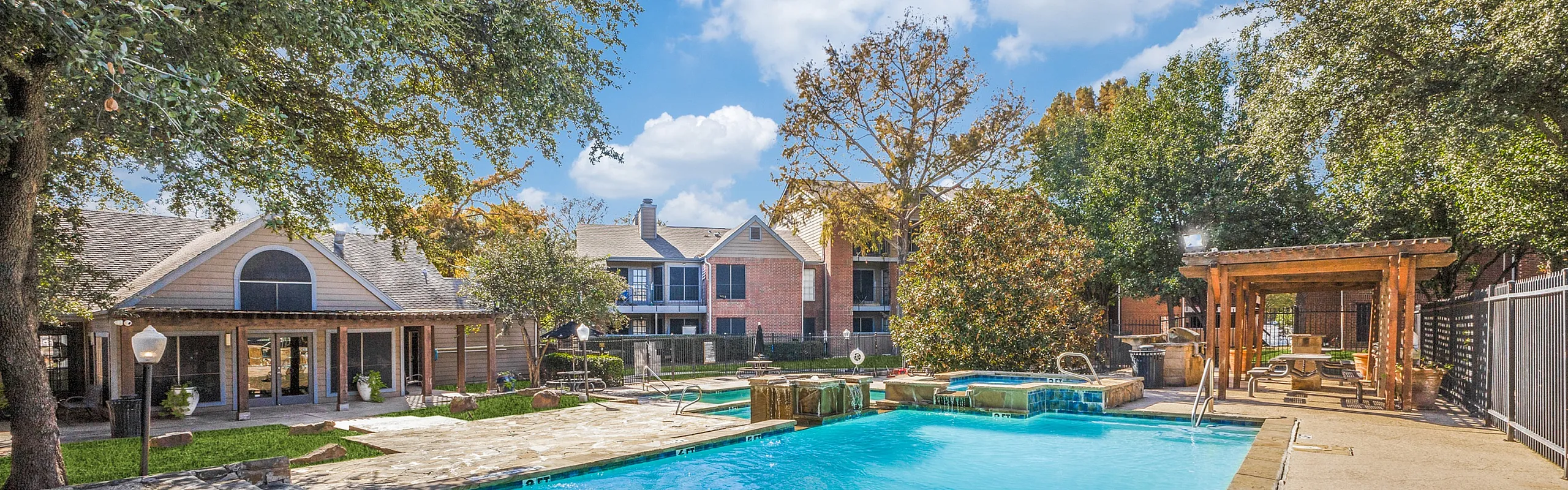 Inviting apartment community with a sparkling pool and relaxing outdoor seating, surrounded by lush greenery and stylish architecture.