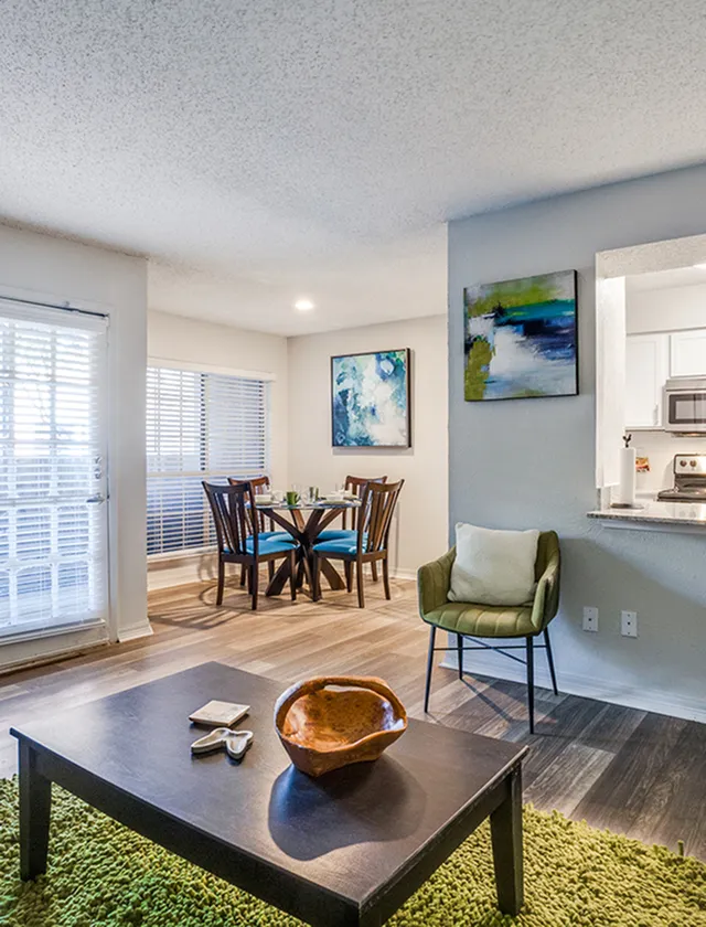 Bright and modern living area with an open dining space, stylish decor, and natural light streaming through large windows.