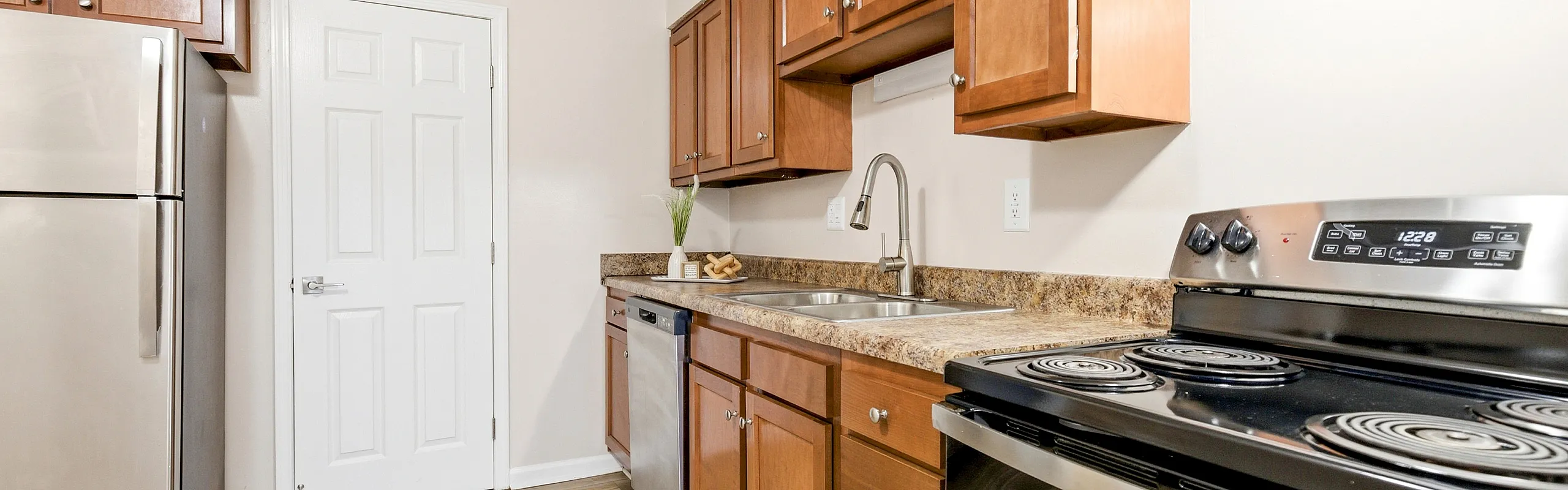Modern kitchen with sleek stainless steel appliances, rich wooden cabinetry, and elegant granite countertops.