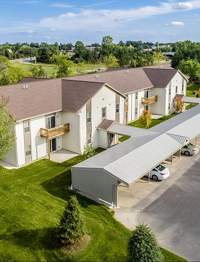 Charming suburban apartment complex with spacious parking, lush green surroundings, and inviting balconies.