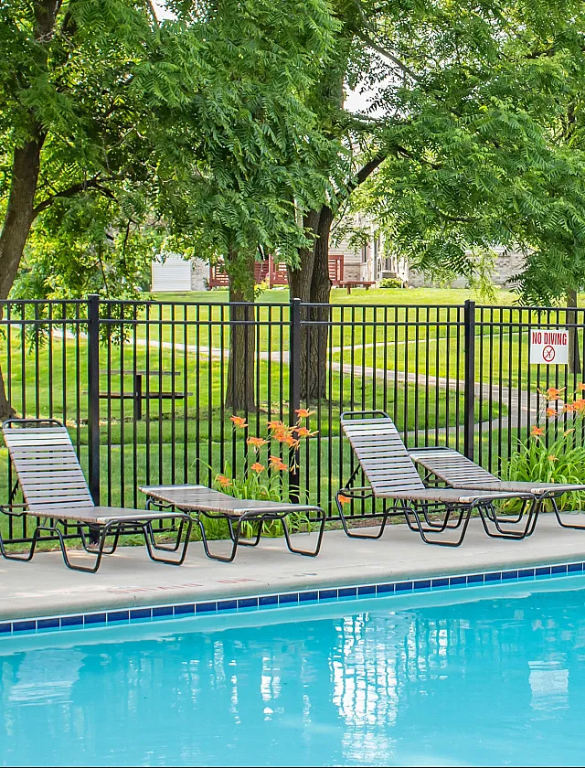 Inviting outdoor pool area with comfortable lounge chairs and lush green surroundings, perfect for relaxation and leisure.