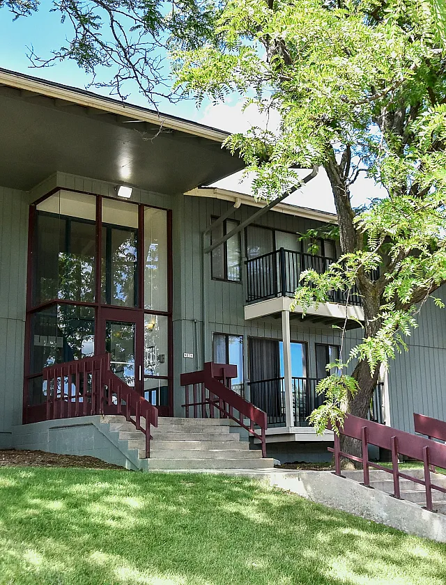 Charming apartment exterior with modern architecture, lush green lawn, and welcoming entrance.