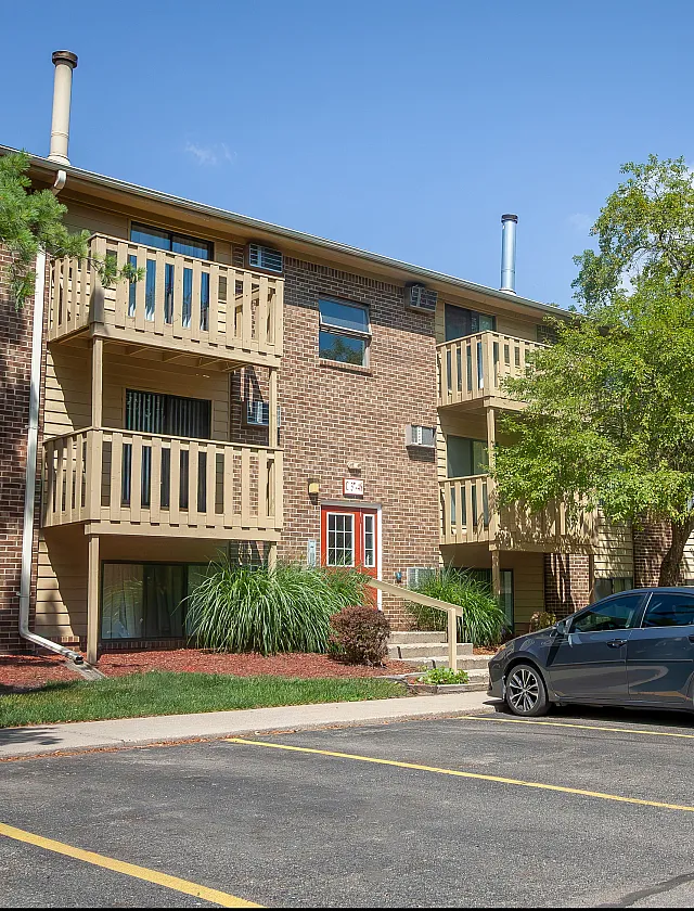 Charming brick apartment building with cozy balconies and well-maintained landscaping, perfect for a vibrant community lifestyle.