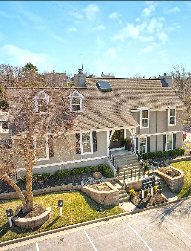 Charming residential building with classic architecture and lush landscaping, offering a welcoming entrance and ample parking.