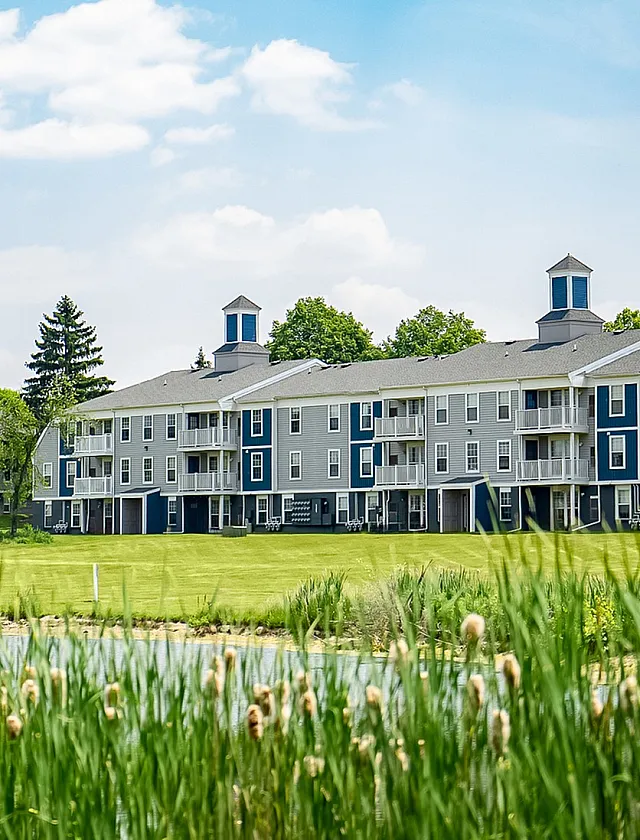 Charming modern apartment building with elegant balconies and a lush green landscape, perfect for serene living.