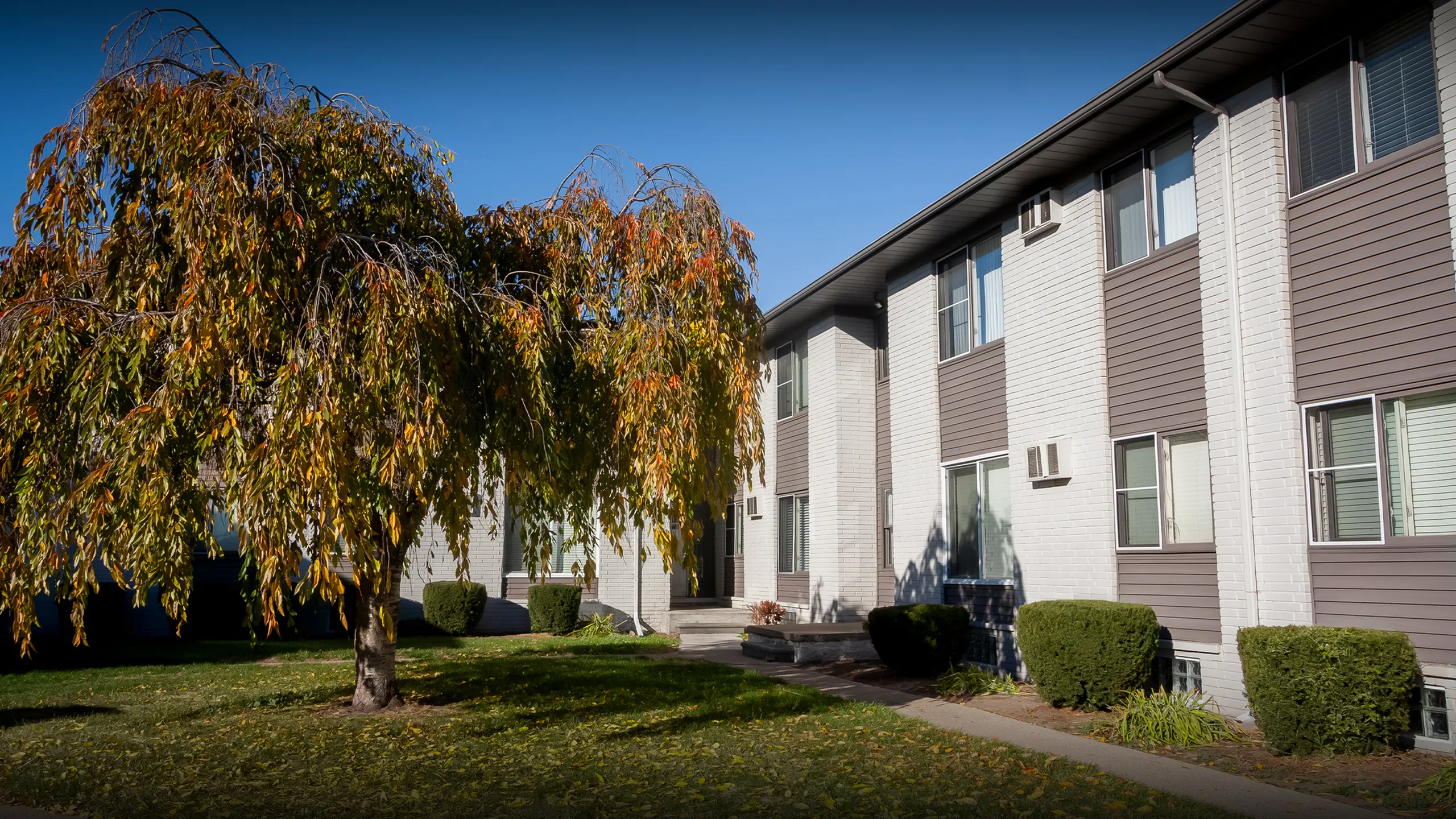 Inviting apartment building with sleek modern facade and lush greenery, offering a warm and welcoming atmosphere.