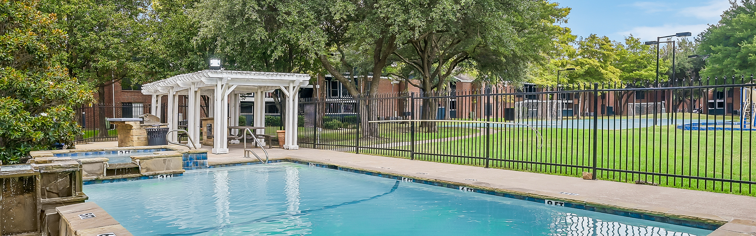 Inviting outdoor pool area with a charming pergola and lush green surroundings, perfect for relaxation and leisure.