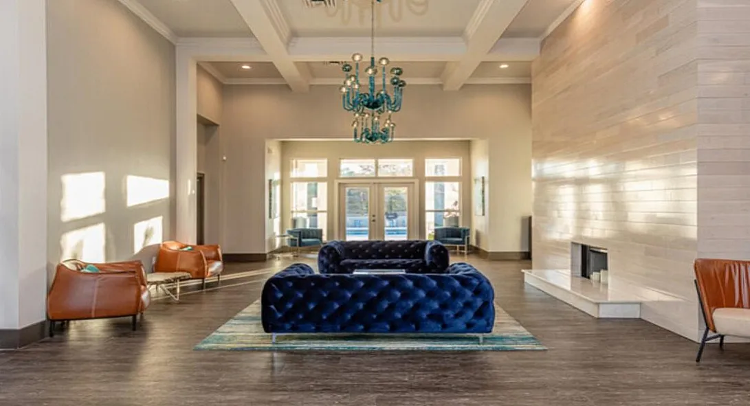 Elegant lobby with plush blue velvet sofas, modern chandelier, and ambient lighting, offering a luxurious welcome.