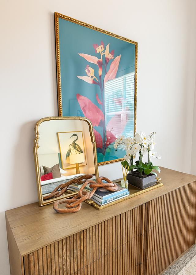 Chic wooden sideboard adorned with elegant decor including a mirror, modern art, and a vibrant orchid arrangement, enhancing the stylish apartment ambiance.