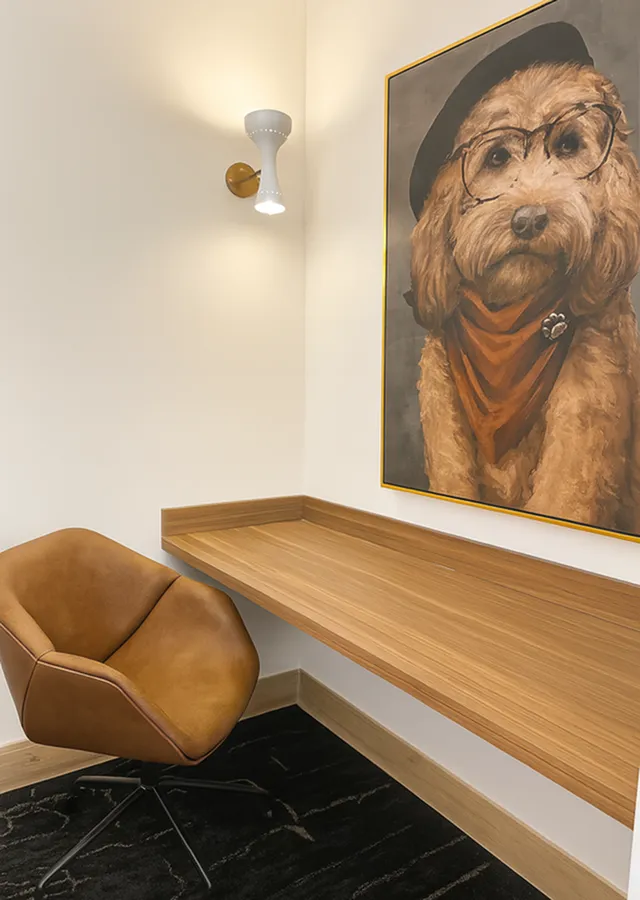 Chic corner office space featuring a modern leather chair, sleek wooden desk, and whimsical dog art creating a cozy and inspiring ambiance.