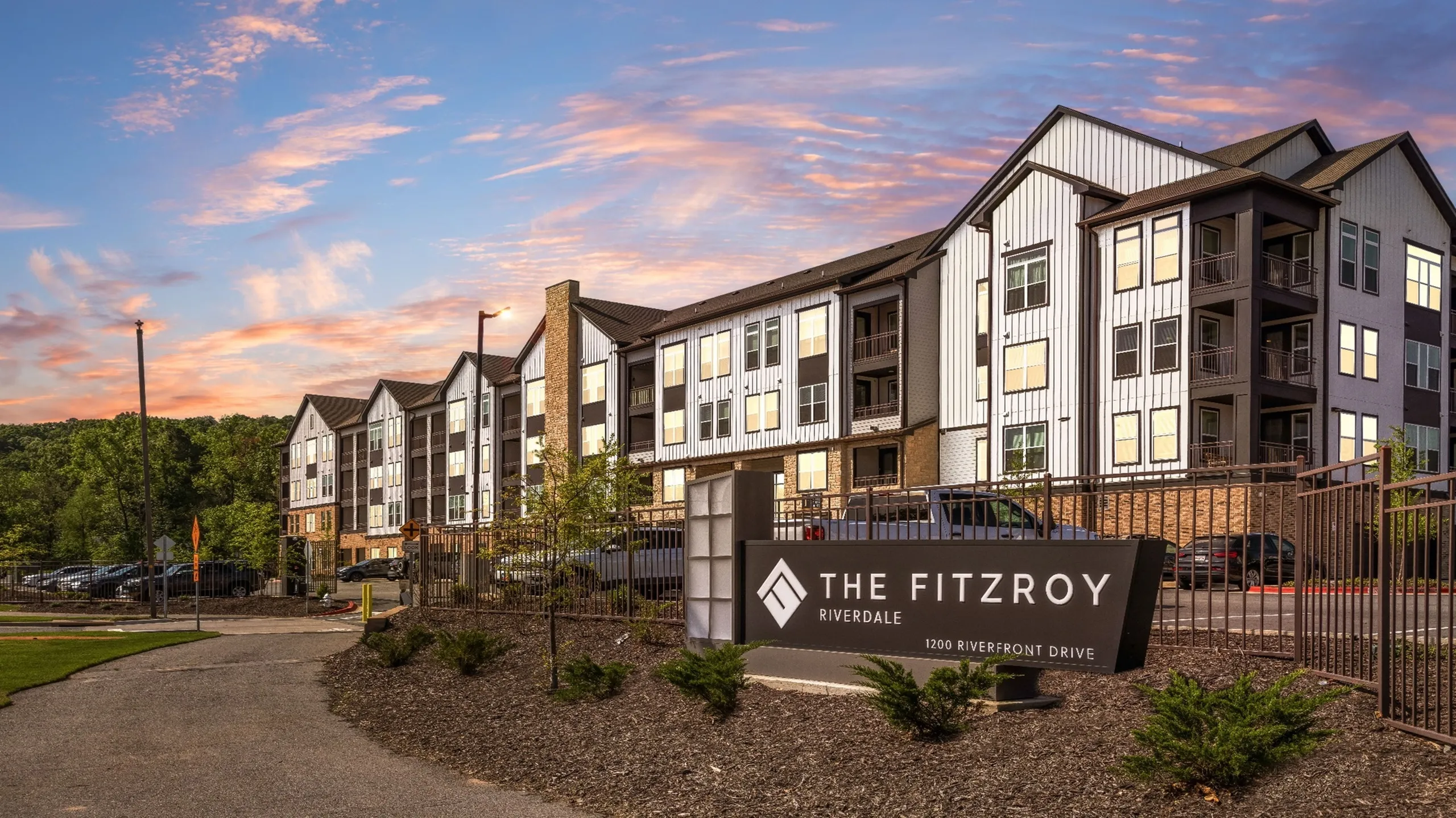 The Fitzroy Riverdale - Modern apartment complex with contemporary architecture set against a picturesque sunset backdrop.