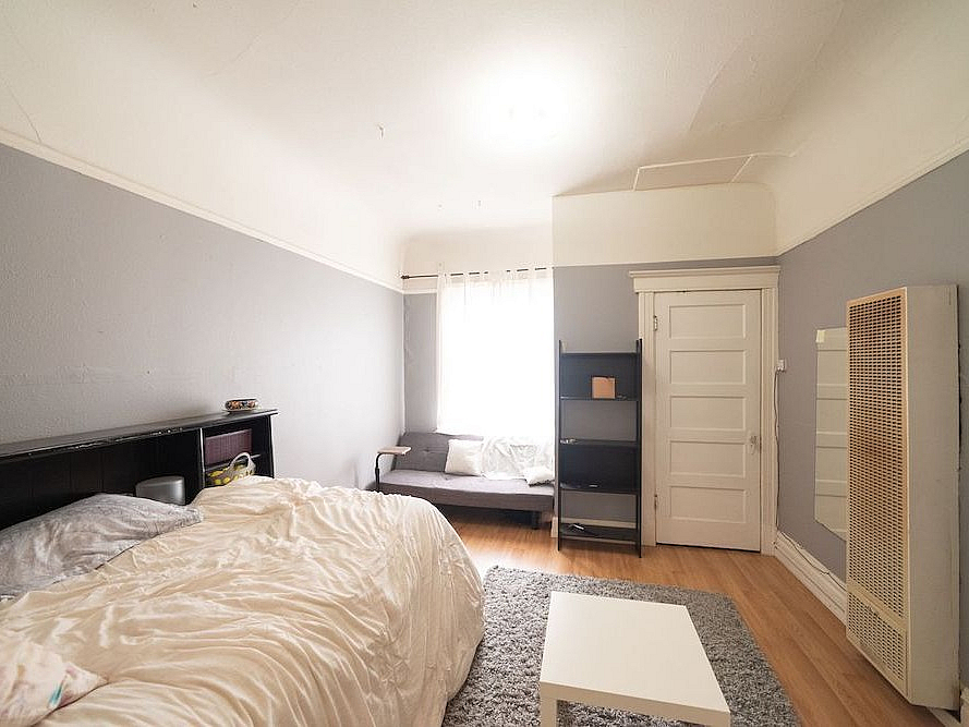 Cozy bedroom featuring a soft bed, elegant shelving, and abundant natural light for a tranquil retreat.