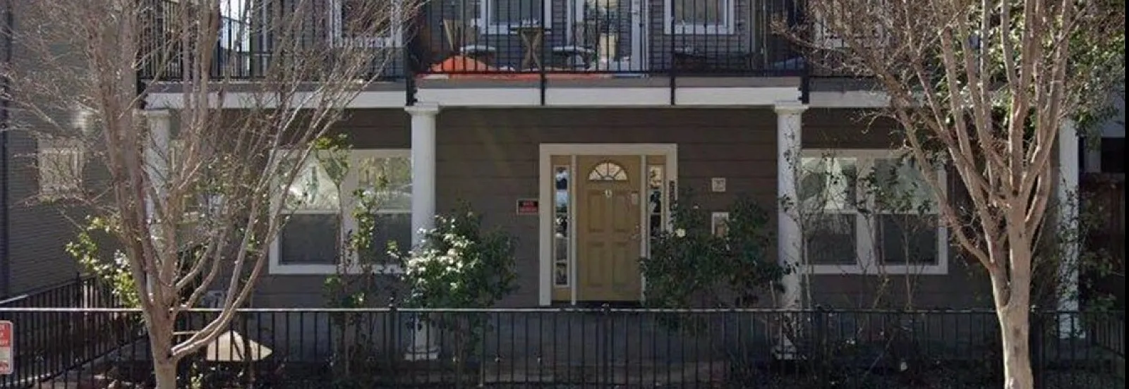 Charming three-story townhouse with inviting balconies, nestled in a peaceful tree-lined neighborhood.