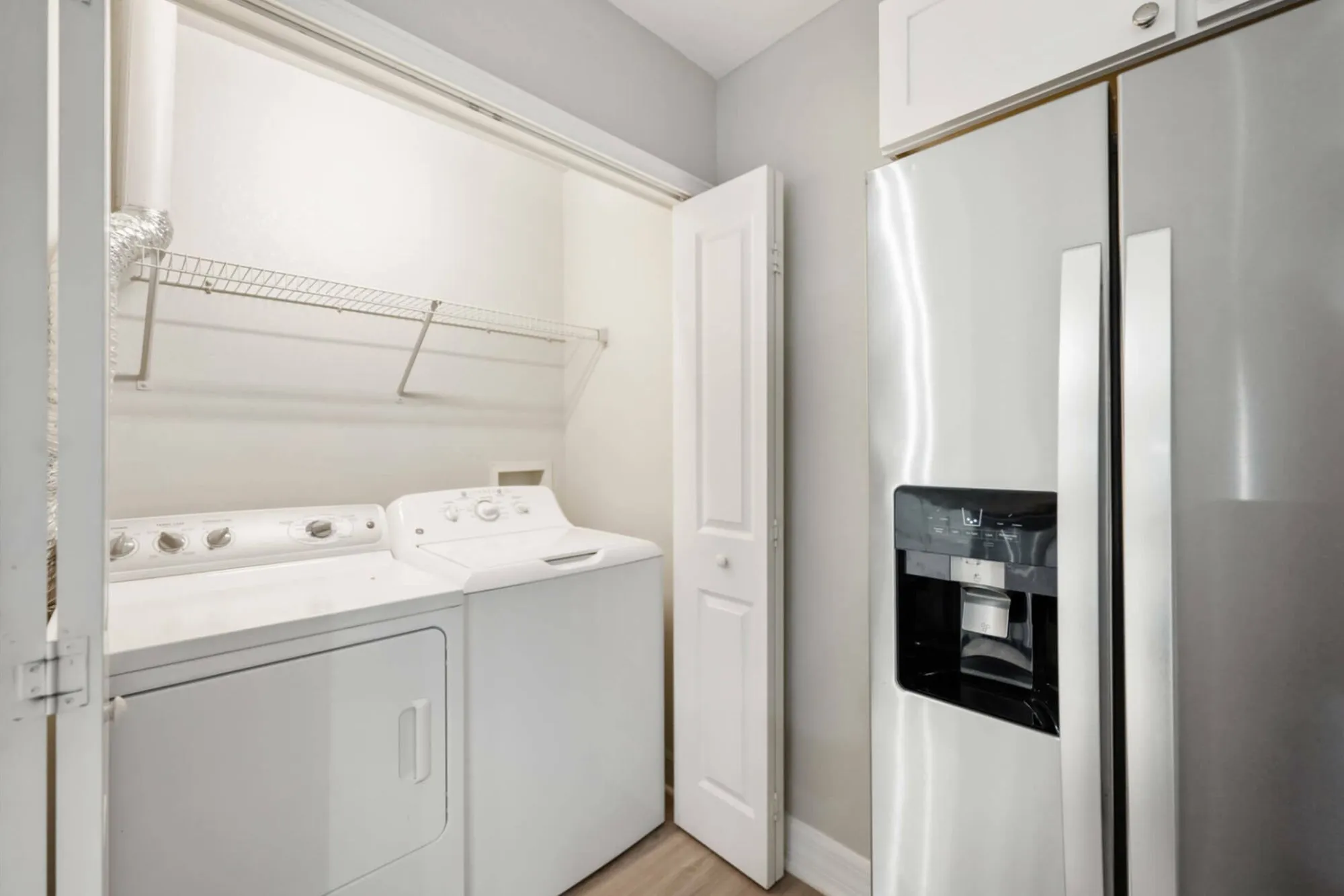 Modern apartment with in-unit laundry featuring a washer and dryer next to a sleek stainless steel refrigerator.