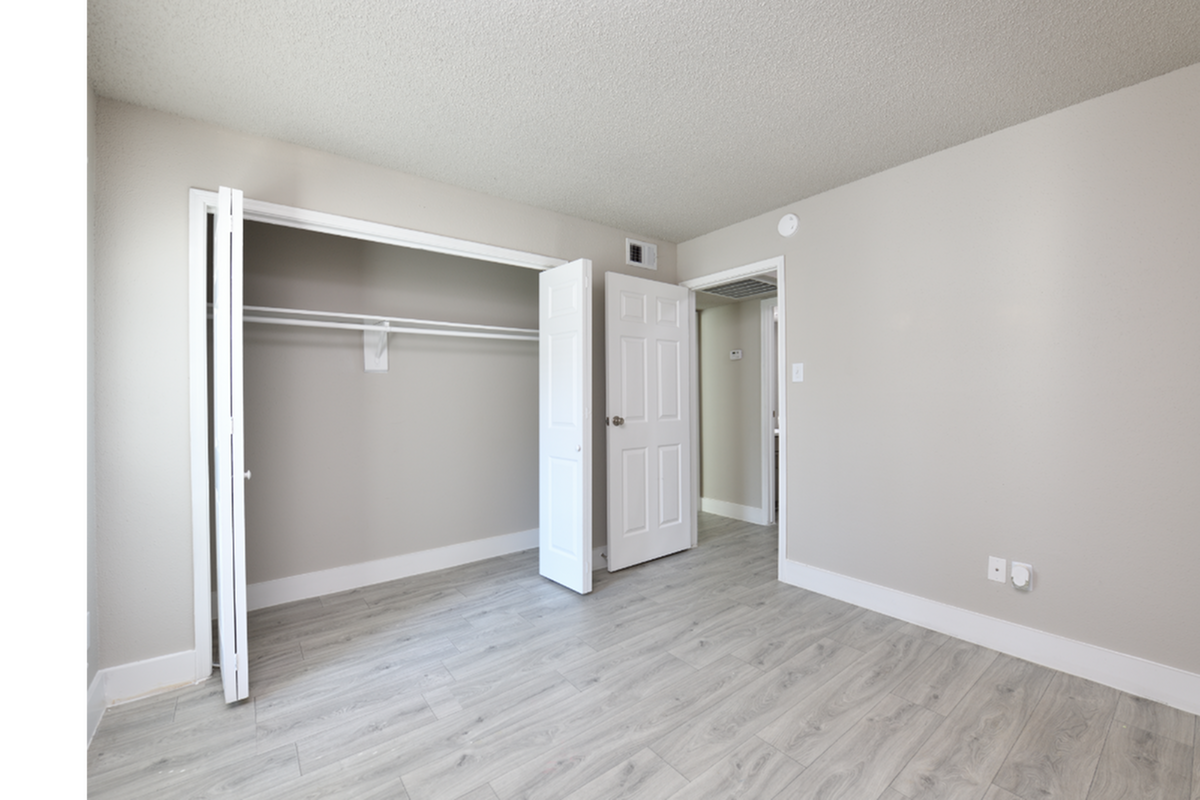 Bright and spacious empty room with light hardwood floors and a built-in closet, perfect for customization and personal touches.