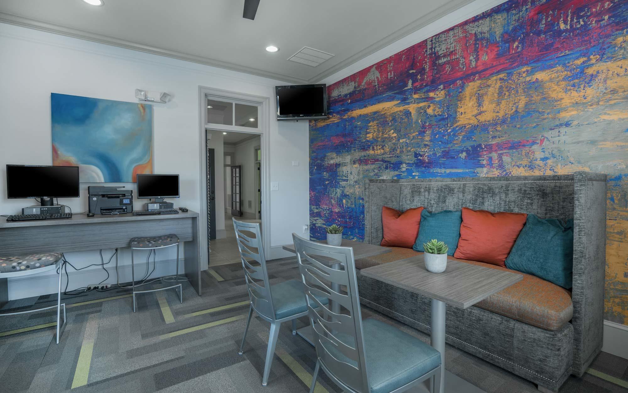 Vibrant seating area with colorful abstract wall art, cozy couch with throw pillows, and modern workstations.