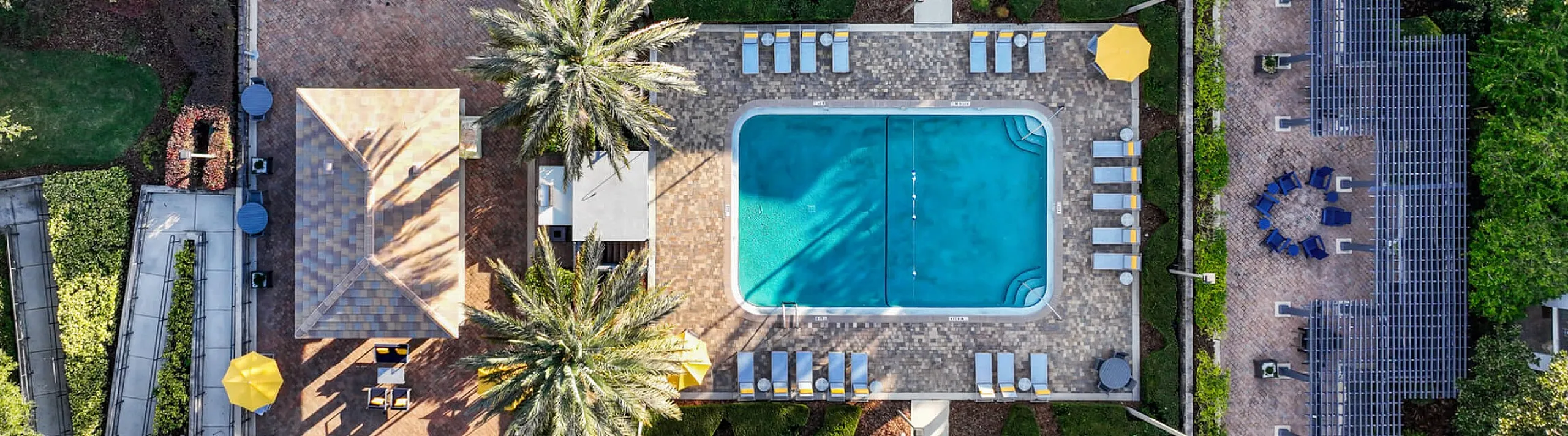 Aerial view of a luxurious apartment complex showcasing a sparkling pool, elegant lounge areas, and lush landscaped gardens surrounded by tranquil pathways.