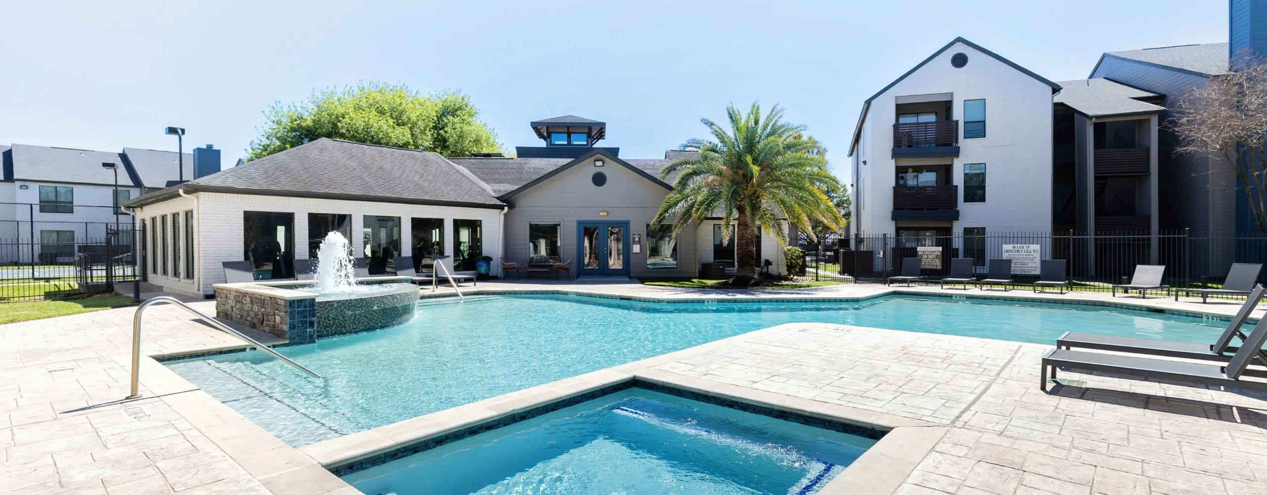 Inviting apartment community with a stunning outdoor pool, modern clubhouse, and lush palm tree landscape.