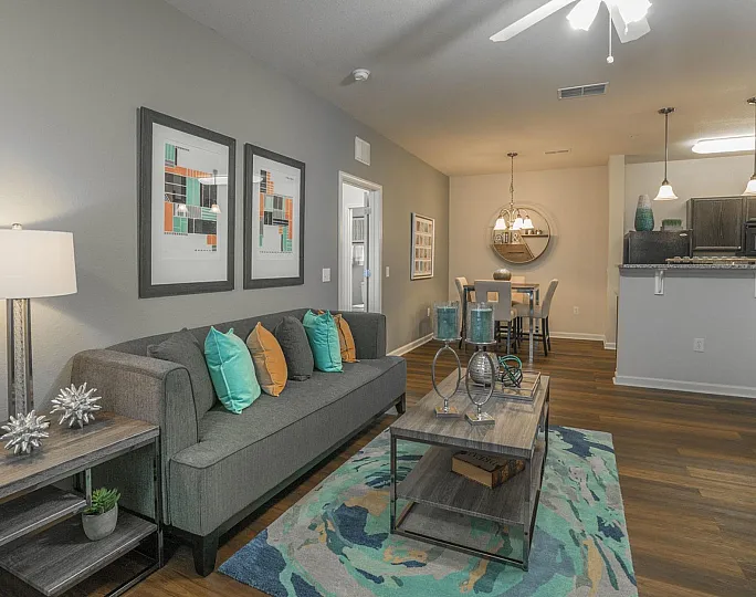 Contemporary open-plan living area with stylish decor, cozy grey sofa, colorful cushions, and elegant dining space next to a modern kitchen.