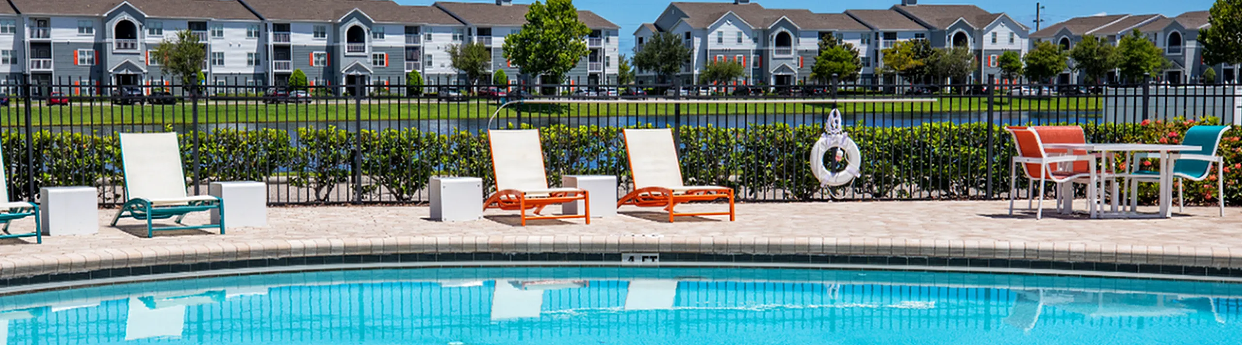 Inviting community swimming pool with comfortable lounge chairs and a scenic view of modern apartments in the background.