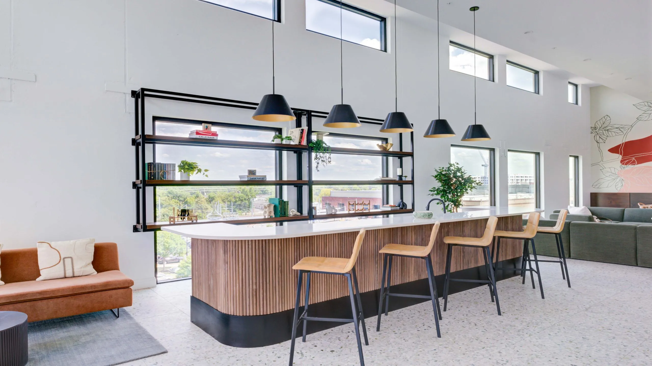 Modern open-concept living space featuring a stylish kitchen island with wooden bar stools, large windows with scenic views, and contemporary decor.