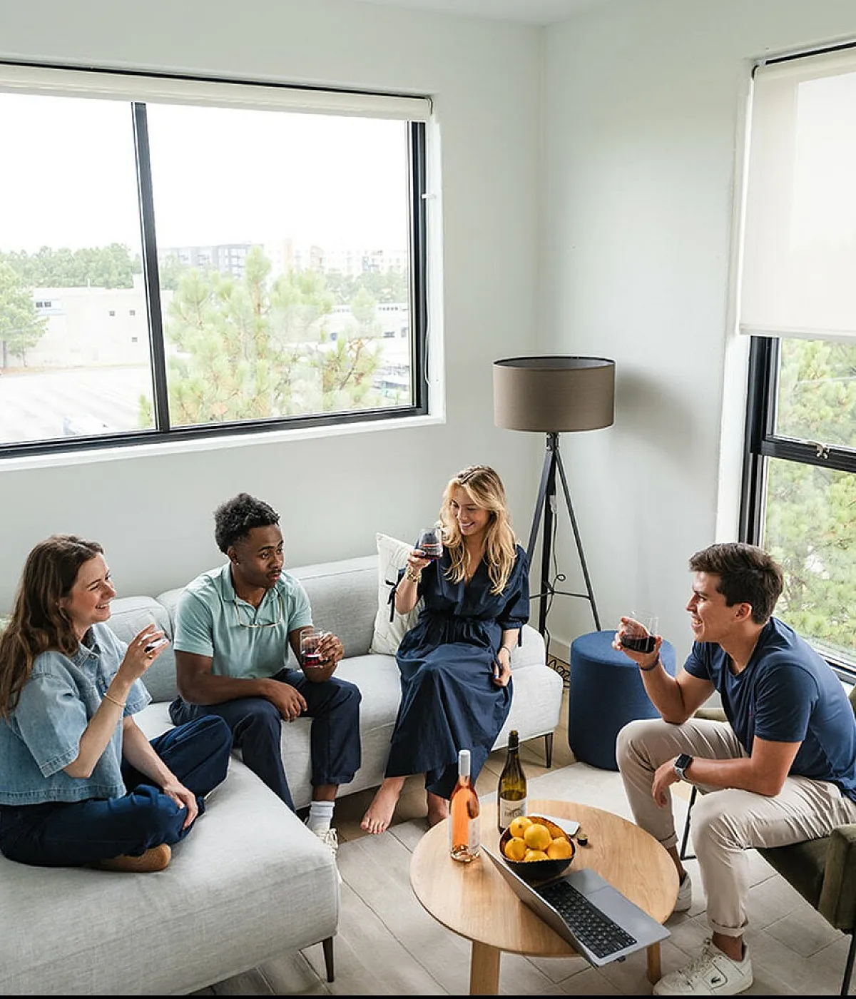 Bright and inviting living room with large windows, cozy seating, and a lively gathering atmosphere.