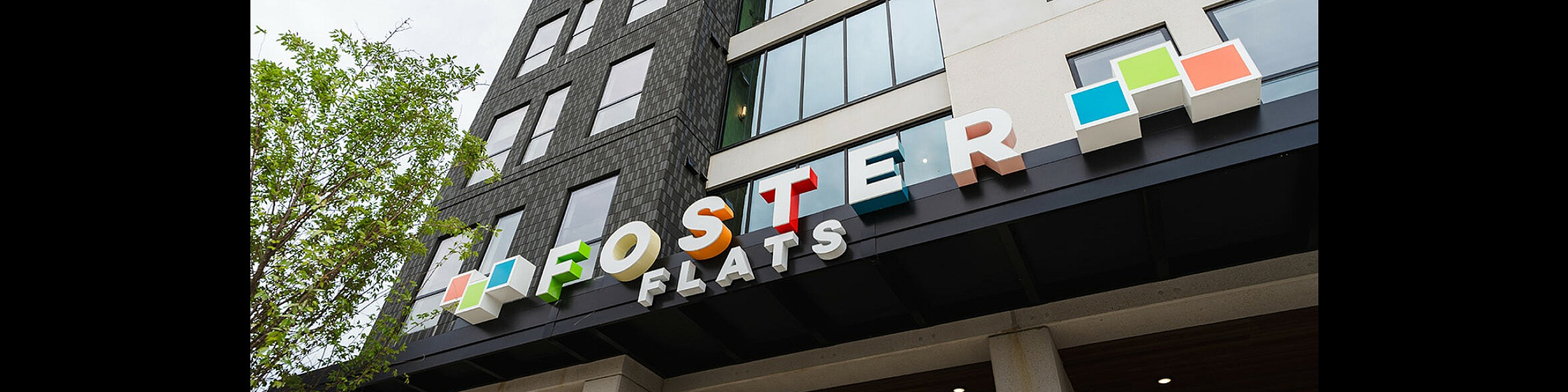 Modern architectural design of Foster Flats with colorful signage and sleek exterior.
