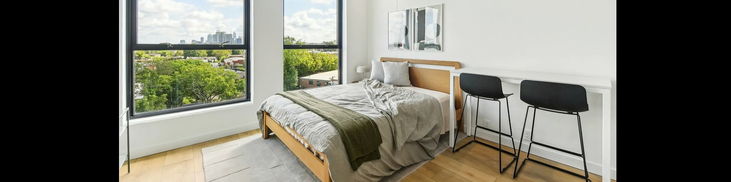 Bright and modern bedroom with panoramic city views, featuring stylish furnishings and ample natural light.