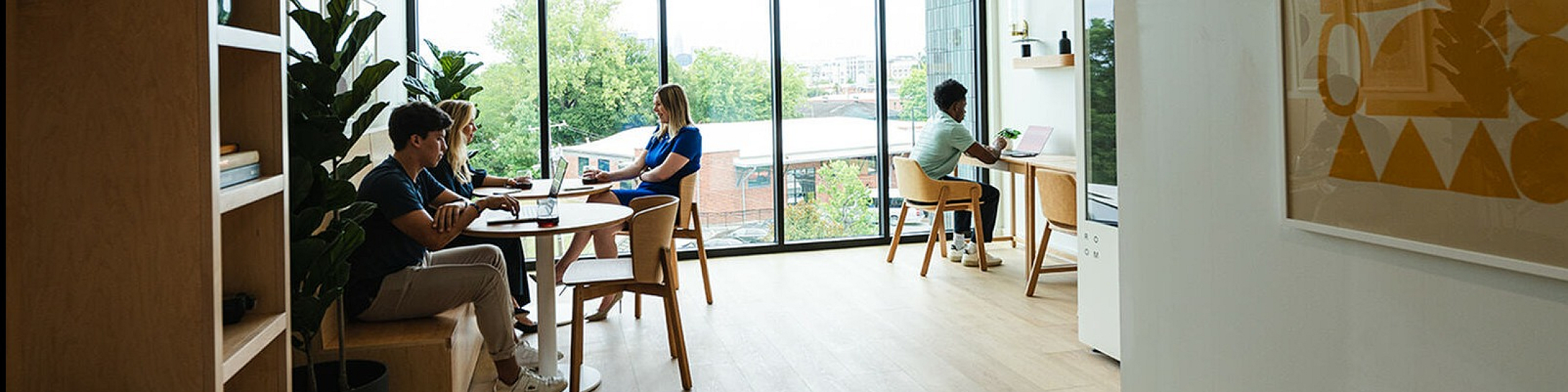 Modern apartment interior with large windows, abundant natural light, and a comfortable workspace. Features stylish decor and greenery for a vibrant atmosphere.