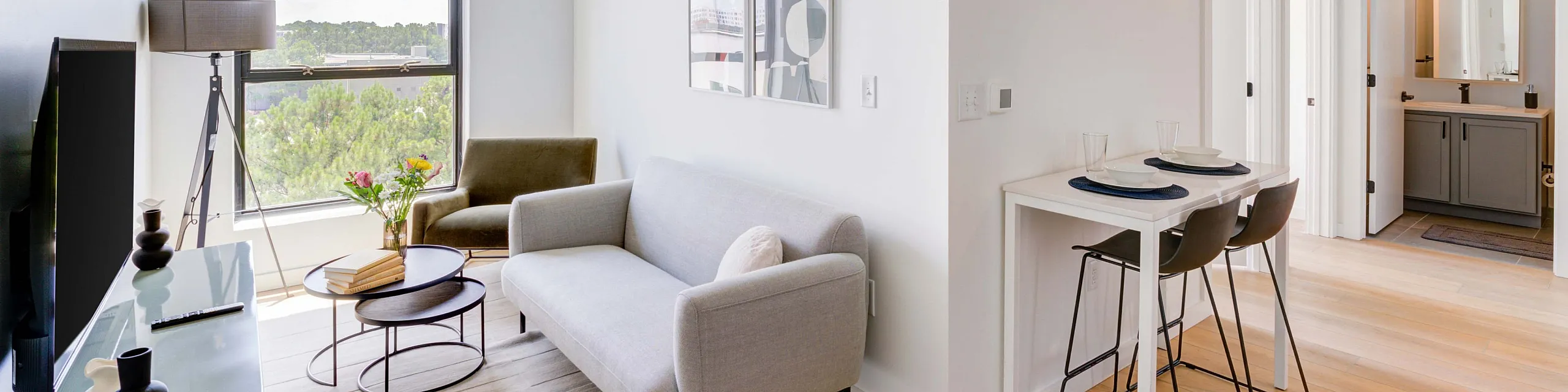 Bright and modern living space featuring a cozy sofa, minimalist decor, and a breakfast nook with a view.