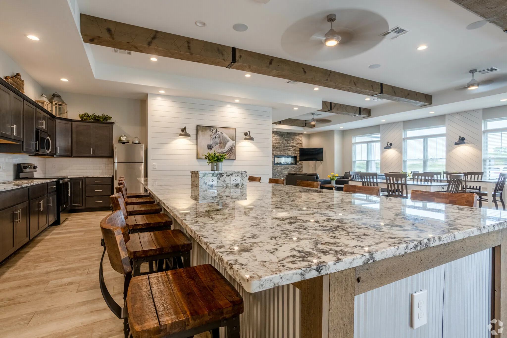 Elegant kitchen and dining area with a granite island, rustic wooden stools, and modern lighting, ideal for entertaining.